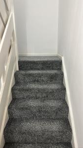 Una escalera en una habitación con alfombra negra en 7 Venus Road (Room 7), en Londres