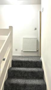 a staircase in a house with white walls and black carpet at 7 Venus Road (Room 7) in London