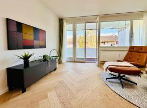 a living room with a chair and a table and window at Modern City Studio with Balcony in Zürich