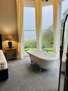 a bath tub in a room with a large window at Luxury garden flat under the Castle in Kent