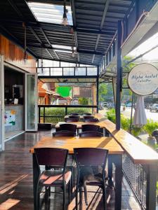 a restaurant with a long wooden table and chairs at ALPHA Hostel Cafe&Bar in Ban Khlong Yai