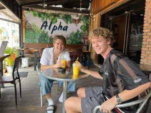 two young people sitting at a table in a restaurant at ALPHA Hostel Cafe&Bar in Ban Khlong Yai