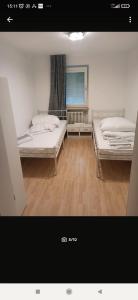 two beds sitting in a room with wooden floors at Entspannter Rückzugsort in Vilshofen an der Donau