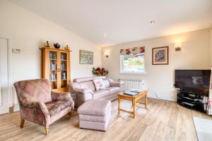 a living room with a couch chair and a tv at Kingfisher Lodge sleeps up to 4 in Crianlarich