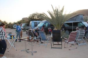 a group of people sitting around tables and chairs in front of tents at Camping , Maison d'hôte Bivouac hyatt-tata in Tatta