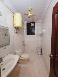 a white bathroom with a toilet and a sink at Raj Residency Inn in Gurgaon