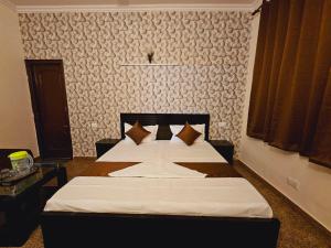 a bedroom with a bed with white sheets and brown pillows at Raj Residency Inn in Gurgaon