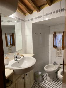 a white bathroom with a sink and a toilet at Casa Della Rosa in Pitigliano