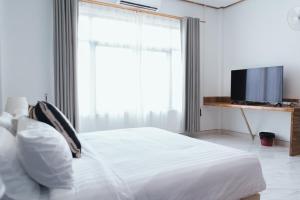 Schlafzimmer mit einem weißen Bett und einem TV in der Unterkunft Tulip Hotel in Louang Namtha