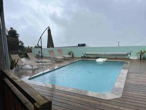 a swimming pool on a deck with chairs and an umbrella at Villa Bois Court 3 chambres in Le Tampon