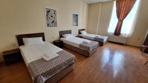 a room with two beds and a large window at Hostel CANTO in Ruse