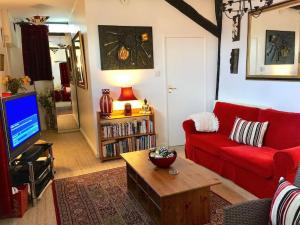 een woonkamer met een rode bank en een tv bij The Barn Delightful secluded Cottage in Heart Old Amersham in Buckinghamshire