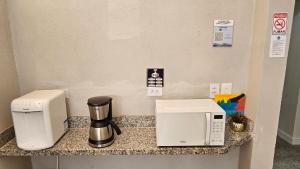 a counter with a coffee maker and a coffeemaker on it at Pousada Aqua in Campo Grande
