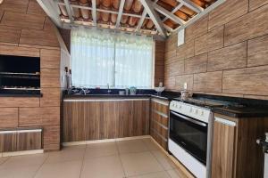 Il comprend une cuisine dotée de murs en bois, d'une cuisinière et d'une fenêtre. dans l'établissement Casa Escarpas do lago, à Capitólio