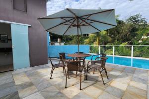 - une table et des chaises avec un parasol sur la terrasse dans l'établissement Casa Escarpas do lago, à Capitólio
