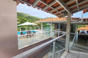 Elle offre une vue extérieure sur une maison dotée d'une terrasse et d'une piscine. dans l'établissement Casa Escarpas do lago, à Capitólio