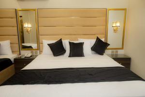a bedroom with a large white bed with black pillows at Hotel white season Gulberg in Lahore