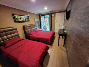 2 posti letto in camera d'albergo con lenzuola rosse di Tamara Guest House a Isola di Tioman