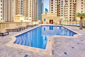 a large swimming pool with benches and buildings at Modern 3BR Flat in the Heart of Dubai JBR in Dubai