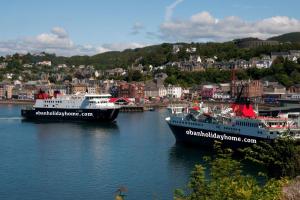 two ships are docked in the water in a harbor at Elmbank Garden Apartment in Oban