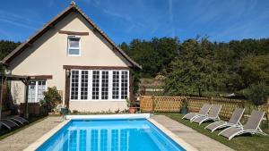 a swimming pool in front of a house with chairs at Au Bonheur de Cisse in Chouzy-sur-Cisse