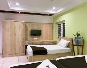 a bedroom with two beds and a flat screen tv at New Thai Residency in Dhārāpuram