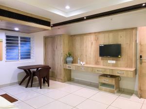 a room with a table and a tv on a wall at New Thai Residency in Dhārāpuram +8 photos