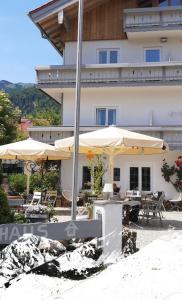 a building with tables and umbrellas in front of it at WuhrsteinHaus in Schleching