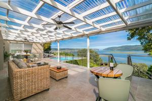 un salón acristalado con ventilador de techo, mesa y sillas en Stunning Villa with pool and views of Knysna, en Knysna
