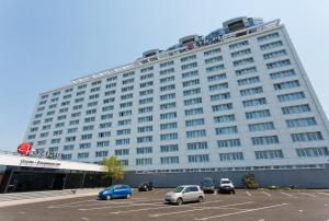 een groot wit gebouw met auto's geparkeerd op een parkeerplaats bij AZIMUT City Hotel Vladivostok in Vladivostok