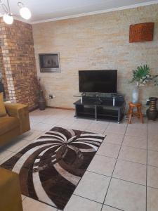 a living room with a flat screen tv on a brick wall at Chappel Hide Out in Germiston