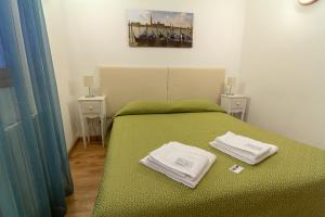 Veneziacentopercento Rooms في البندقية: غرفة نوم بسرير اخضر عليها مناشف