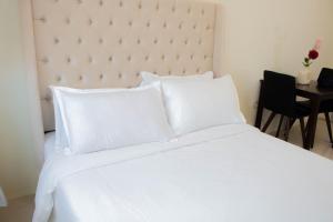 uma cama branca com lençóis e almofadas brancos em Vitasolo Hometel & Suite em Tagum