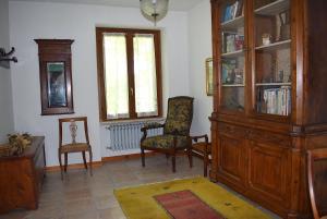 a living room with a large wooden cabinet and chairs at Casa Vacanze Cascina Campagnola in Pozzolengo