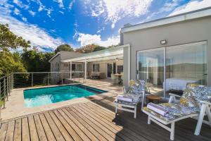 a deck with a pool and a house at Stunning Villa with pool and views of Knysna in Knysna