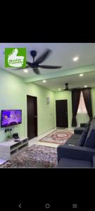 een woonkamer met een bank en een flatscreen-tv bij Sri Aman Homestay in Jitra
