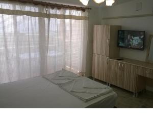 a bedroom with a bed and a dresser and a television at Palmaris Apart Palamutbuku in Palamutbuku