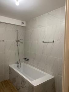 a white bath tub in a bathroom with marble tiles at Modern and well done flat Geneva - self check-in in Saint-Genis-Pouilly