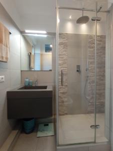 uma casa de banho com uma cabina de duche em vidro e um lavatório. em Terrazza18 em Milão