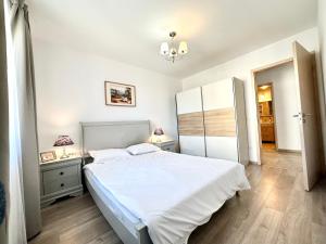 a bedroom with a white bed and two night stands at Kasper Coresi Mall - Rise Private Apartments & Suites in Braşov