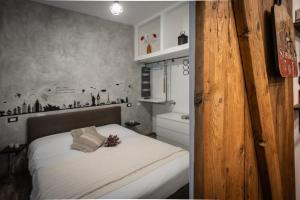 una piccola camera con un letto bianco e una porta in legno di Civico 65 ad Arezzo