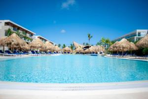 a large swimming pool with straw umbrellas and chairs at Serenade All Suites - Adults Only Resort in Punta Cana