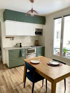 cocina con mesa de madera y armarios verdes en Charmant appartement au cœur du 11e arrondissement en París