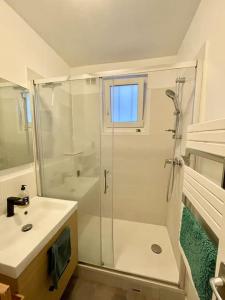 baño blanco con ducha y lavamanos en Charmant appartement au cœur du 11e arrondissement en París