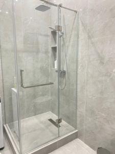 La salle de bains est pourvue d'une douche avec une porte en verre. dans l'établissement Batysmura Бизнес, à Atyraū