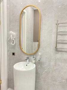 La salle de bains est pourvue d'un lavabo blanc et d'un miroir. dans l'établissement Batysmura Бизнес, à Atyraū