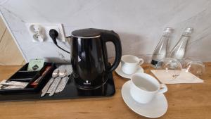 eine Kaffeemaschine auf einem Tisch mit Tassen und Weinflaschen in der Unterkunft Hotel & Restauracja Wróblewscy in Karniewo