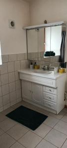 bagno con lavandino bianco e specchio di Chez Julien a Bréal-sous-Montfort
