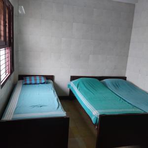 duas camas num pequeno quarto com lençóis azuis em G R MANSION em Vellore
