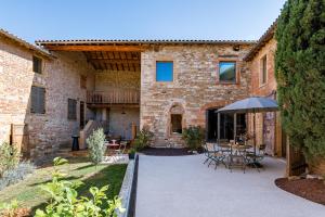 eine Außenterrasse mit einem Tisch und einem Sonnenschirm in der Unterkunft Maison de Pagneux in Lachassagne